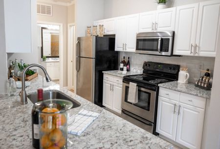 Duluth, GA luxury apartments - Parc 85 - Kitchen with Granite-Style Countertops, White Cabinets, and Stainless Steel Appliances.