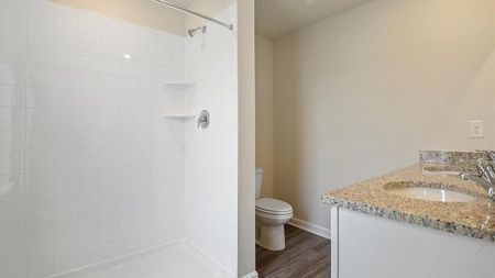 unfurnished bathroom with standing shower, toilet and sink in townhome