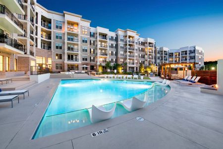 furnished pool area with apartment building at dusk