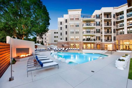 furnished pool area with apartment building at dusk