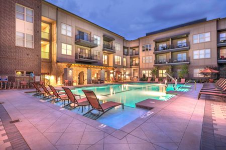 exterior pool with patio furniture and apartment building at night