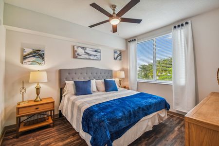 One BR Apartments in Delray Beach, FL - Congress Grove - Bedroom with Wood-Style Flooring, Bed, Nightstands, Lamps, Dresser, Ceiling Fan, and Window.