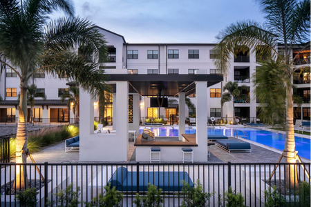 grilling area with pool and apartment building at dusk