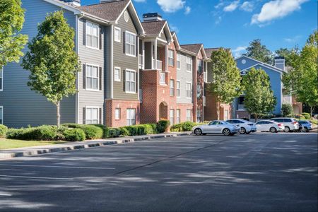 exterior apartment building with cars in parking lot on sunny day