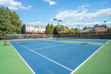 tennis courts with apartment buildings in background on sunny day