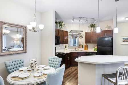 Apartments Near County Park - Apartments at Shade Tree - Kitchen with Espresso Cabinets, White Quartz Countertops, Black Appliances, Dining Island, and Wood-Style Flooring
