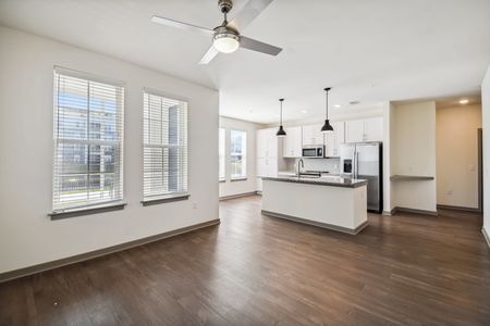 Modern Apartments in Orlando - The Landings at Boggy Creek - Open-Concept Living Room with View of Kitchen, Large Windows, and Ceiling Fan.