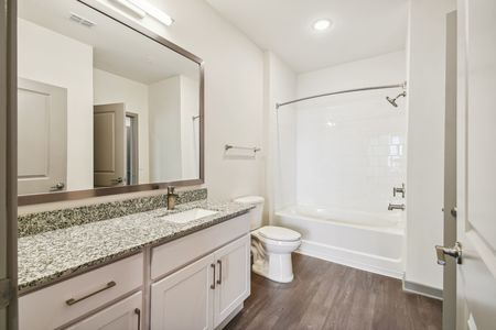 spacious guest bathroom with tub and wood style flooring