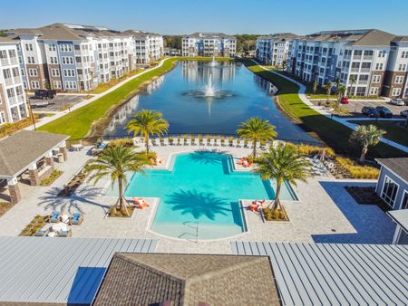 Birds eye view of community pool and pond in center of apartment community