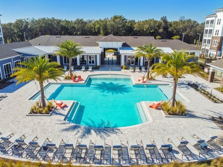 Apartments near Orlando International Airport - The Landings at Boggy Creek -Resort-Style Pool with Lounge Chairs and Palm Trees.
