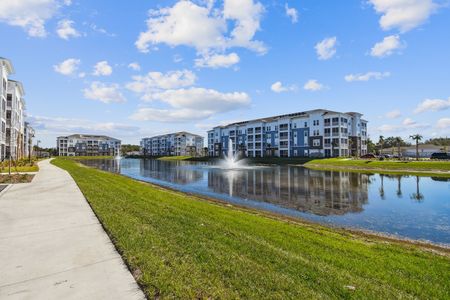 Sidewalk and exterior apartment buildings surrounding a pond on a sunny day