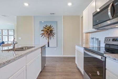 Furnished kitchen with stainless steel appliances and white cabinets