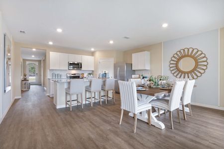 View of the furnished dining area and kitchen with stainless steel appliances and white cabinets