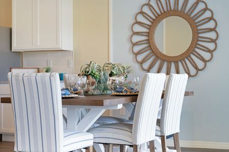 Dining room table with greenery decorations and wall mirror on wall