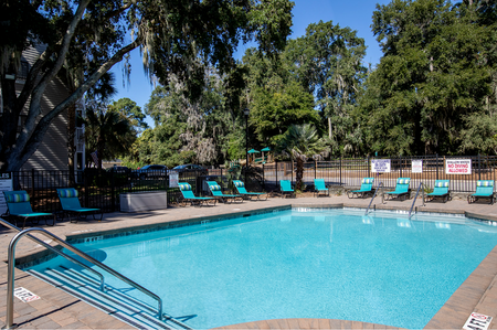Pet Friendly Apartments in Port Royal SC - Preserve at Port Royal - Gated Pool with Lounge Chairs, Surrounded by Trees.