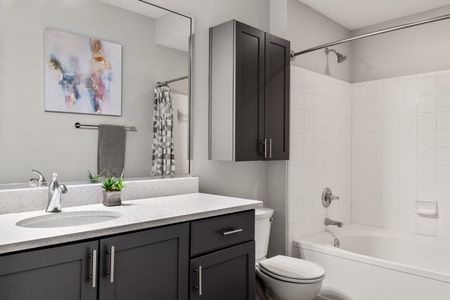 furnished bathroom with sink, toilet and shower tub in apartment home