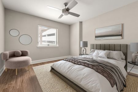 Furnished bedroom with lighted ceiling fan and bed with sitting chair in corner