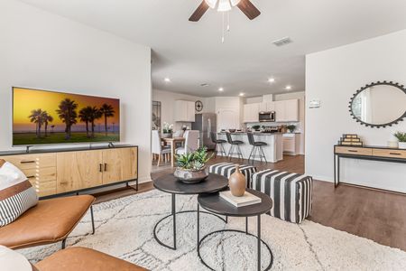 Furnished living room with chairs, ceiling fan and television with a view of the kitchen
