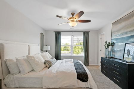furnished bedroom model with windows and ceiling fan