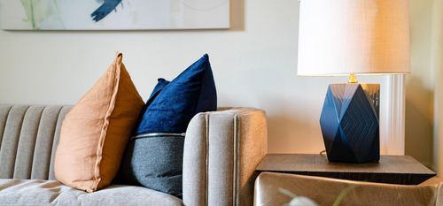 sofa and side table with pillows and table lamp in living area