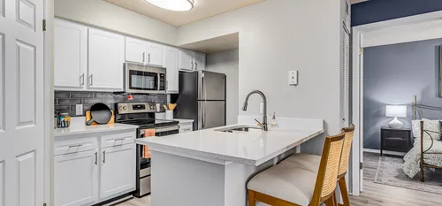 Contemporary kitchen with white cabinets, stainless steel appliances, and a breakfast bar with stools.