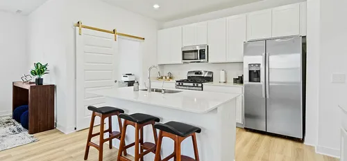 Upscale kitchen with white cabinets barn door and stainless steel appliances