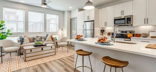 decorated kitchen with white cabinets and tile backksplash. Open floor plan leading into living area.