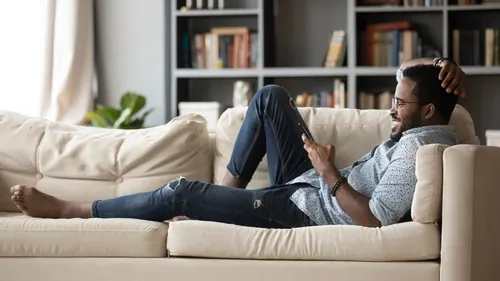man on phone while lying on couch in living room
