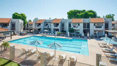 Expansive apartment complex with a stunning outdoor pool and sun loungers.