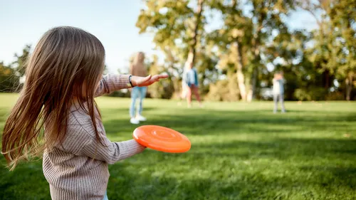 little girl throwing a frisbee in the park