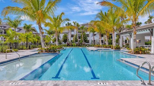 Exquisite resort-style swimming pool surrounded by lush palm trees and chic outdoor seating, perfect for relaxation and leisure.