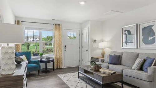 Bright and stylish living room with cozy grey sofa, chic coffee table, and elegant decor, featuring a large window with yellow patterned curtains offering a scenic view outside.