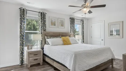 Bright and airy bedroom featuring elegant decor, large windows, and a cozy bed with stylish wooden furniture.