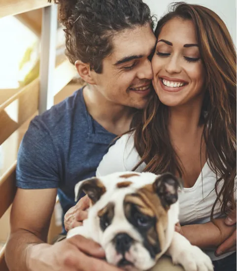 man and woman with dog in lap