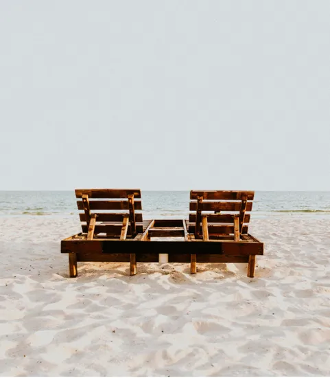 Two empty beach chairs on the sand facing the ocean