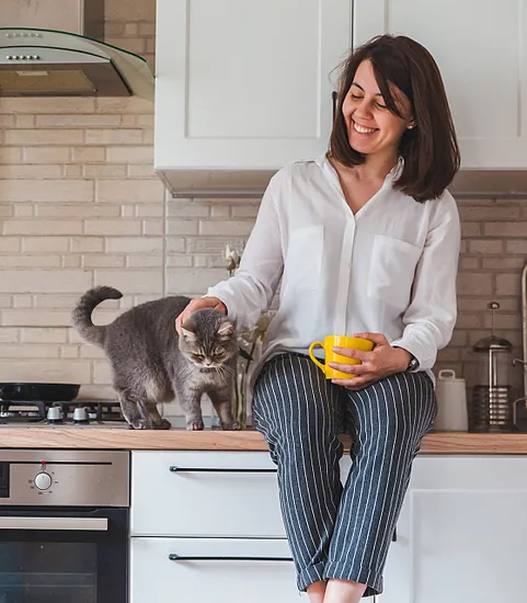 woman sitting on kitchen counter with a cat