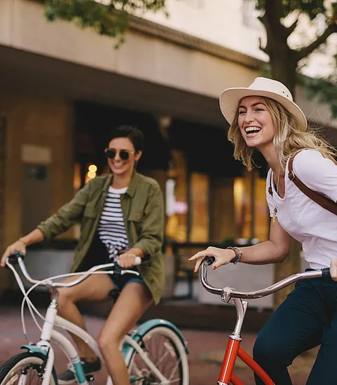two stylish women riding bikes outdoors