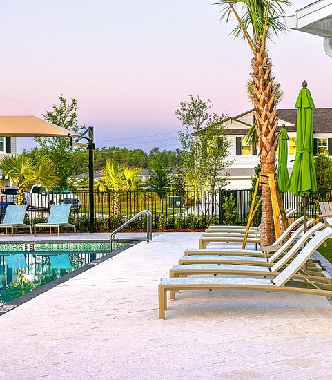 Luxurious outdoor pool area with sun loungers, palm trees, and a serene sky, perfect for relaxation and leisure.
