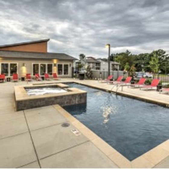 Outdoor swimming pool with an included jacuzzi and lounge seating near UARK