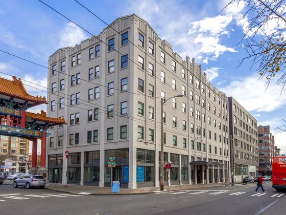 Street view of The Publix building in Seattle's Chinatown-International District, with the historic Chinatown gate and a BoltBus visible nearby