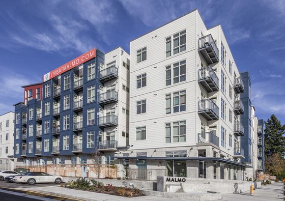 Exterior of Malmo Apartments with white and blue siding and balconies.