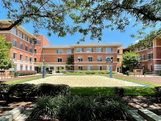 Walker Avenue Apartments building seen behind courtyard trees and volleyball court