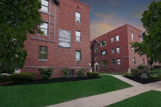 Charming brick apartment buildings with lush green landscaping and a welcoming pathway at sunset.
