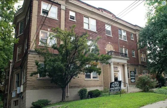 Charming historic apartment building with elegant architecture and lush greenery in a vibrant neighborhood.