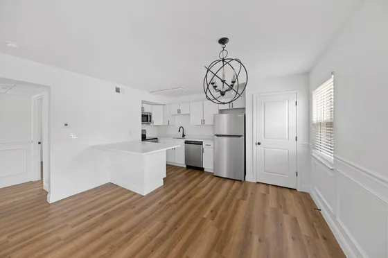 Modern kitchen with sleek white cabinetry, stainless steel appliances, and elegant hardwood flooring.