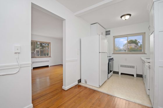 Bright and inviting kitchen with modern appliances and a cozy adjacent living area featuring elegant hardwood floors.