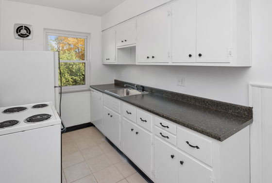Charming kitchen with elegant white cabinetry, a sleek black countertop, and a cozy window view.