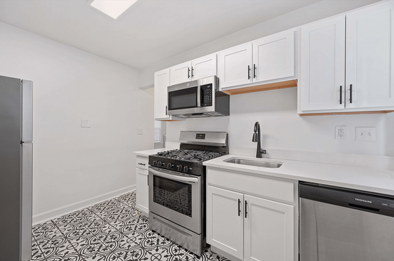 Modern kitchen featuring sleek white cabinetry, stainless steel appliances, and elegant patterned flooring.
