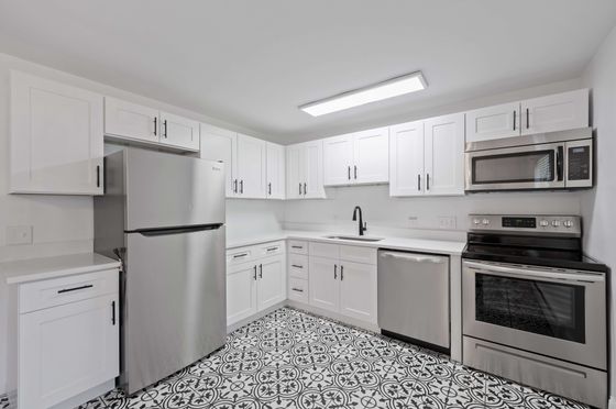 Sleek and modern kitchen featuring stainless steel appliances, elegant cabinetry, and stylish patterned flooring.