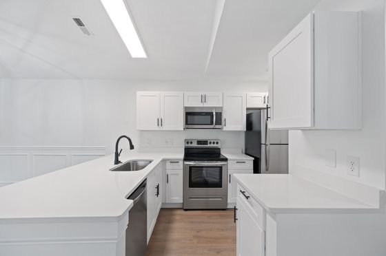 Modern kitchen with sleek white cabinetry, stainless steel appliances, and spacious countertops, perfect for culinary enthusiasts.